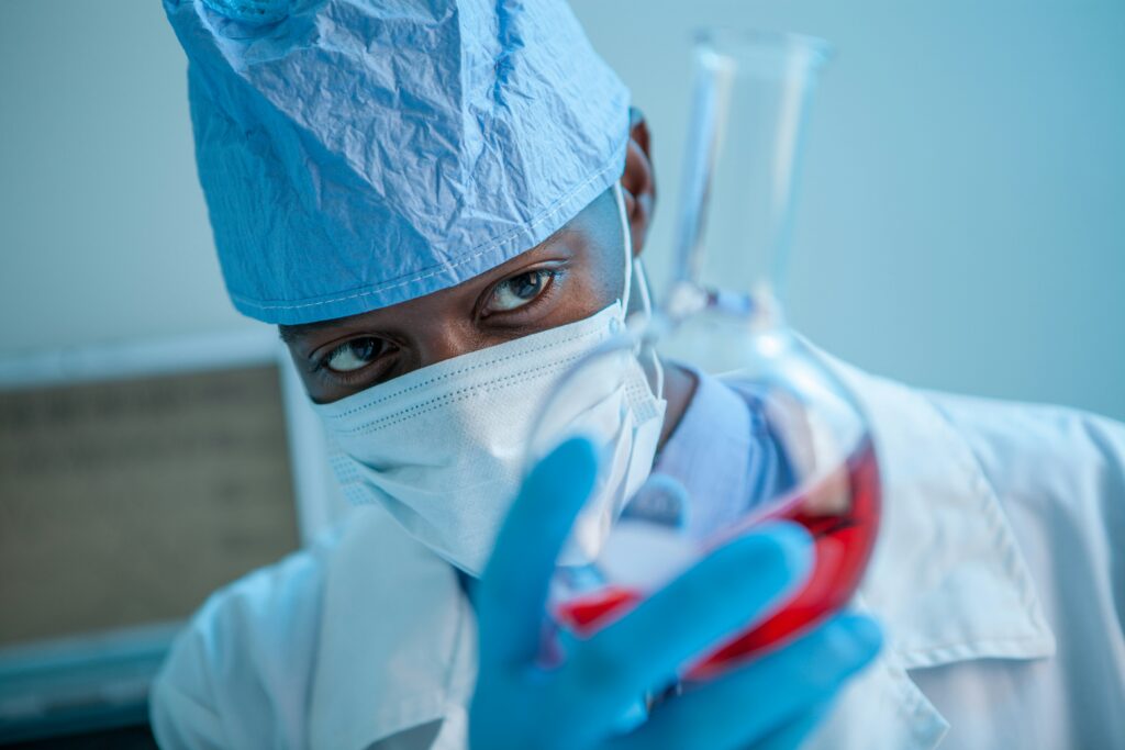 A doctor looking at a flask of red liquid