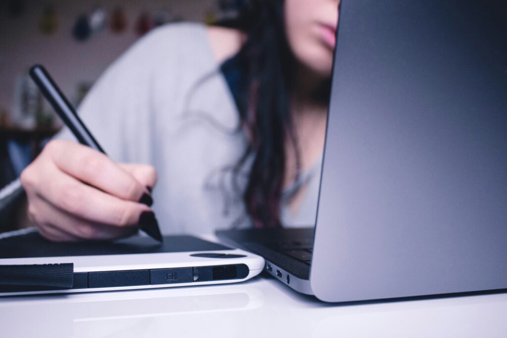 Person looking intently at a laptop screen while holding a tablet pen