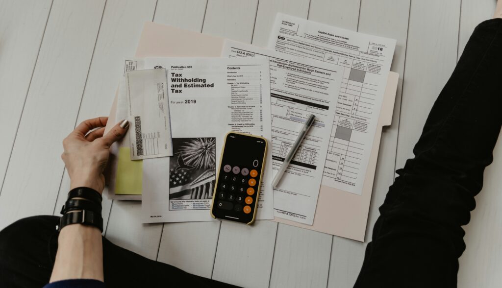 A person going over tax documents with the calculator app on their phone